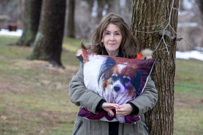 宠物主人朗达·鲍威尔与印有她已去世的爱犬照片的枕头合影。.png